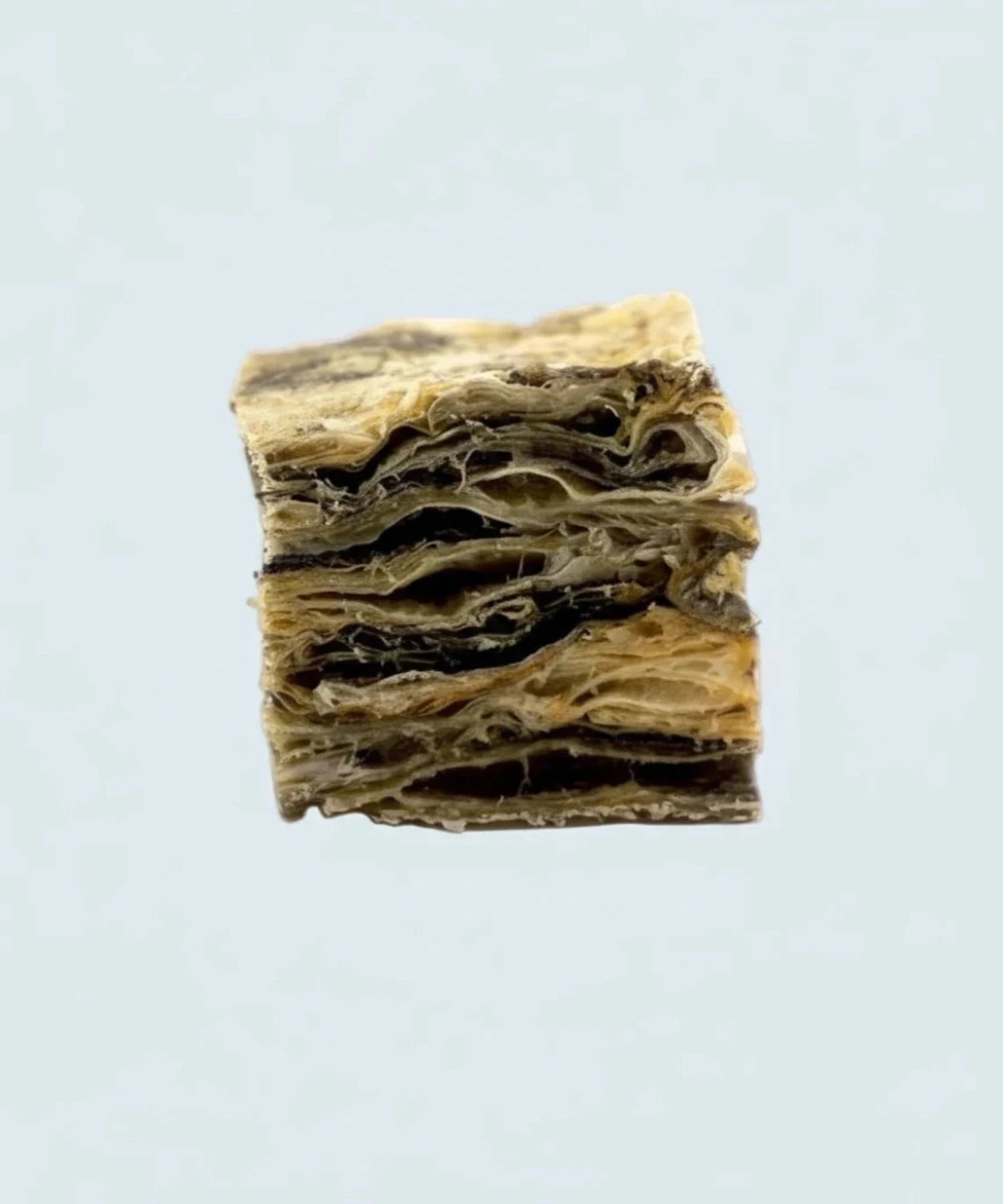 Close-up of a layered fish skin cube on a light background, dental treats category banner.