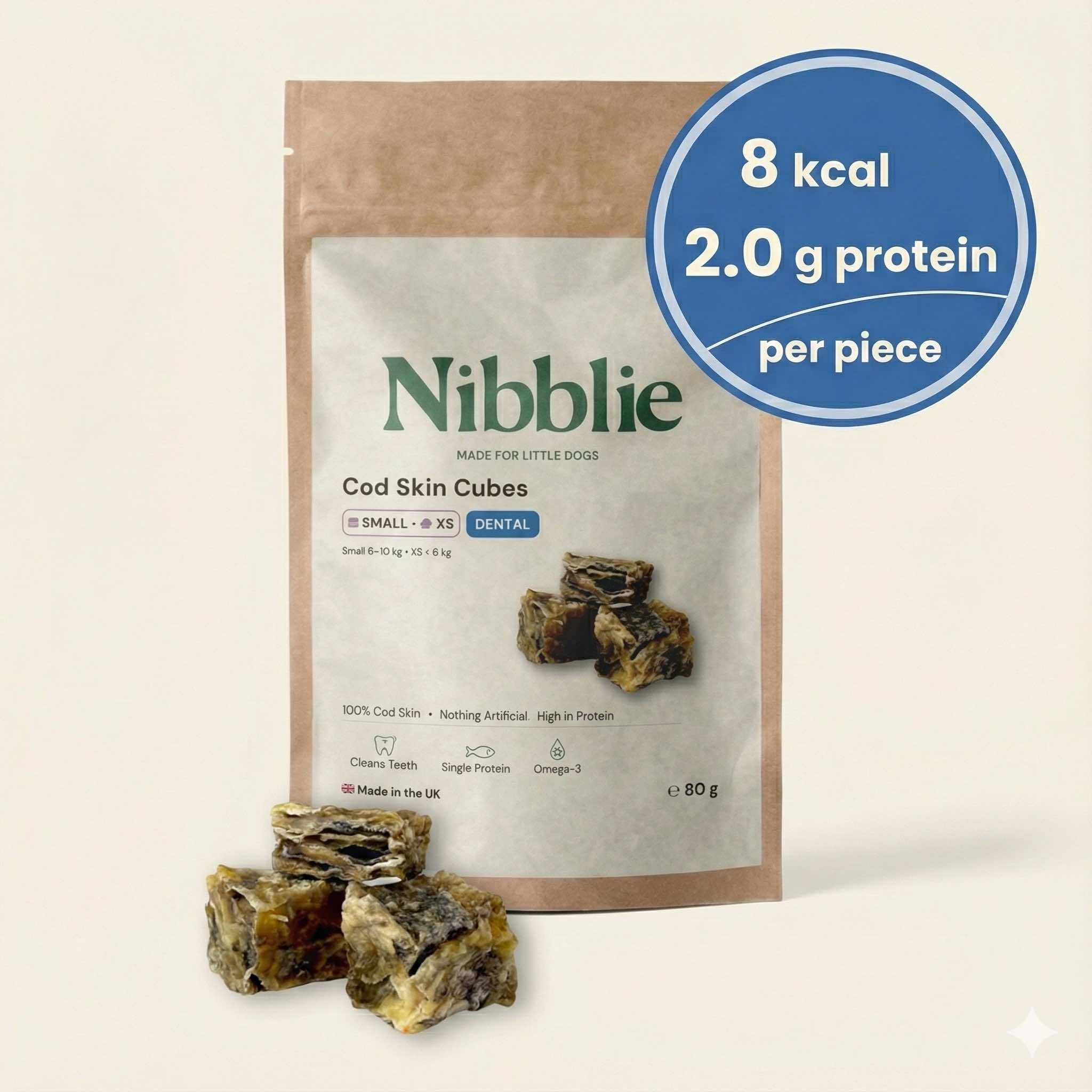 Nibblie Cod Skin Cubes 80g pack on warm linen with cubes in front; natural low-cal fish-skin dental treats for small dogs.