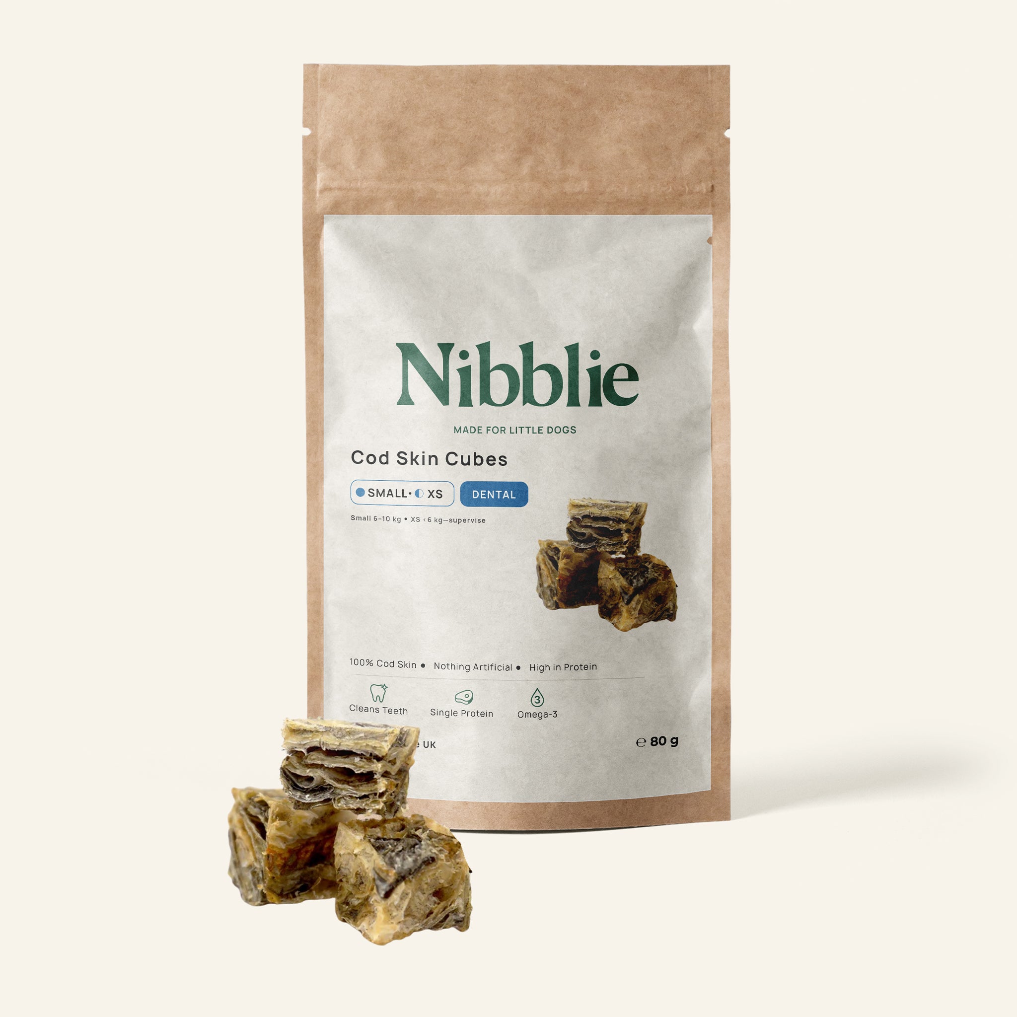 Nibblie Cod Skin Cubes 80g pack on warm linen with cubes in front; natural fish-skin dental treats for small dogs.