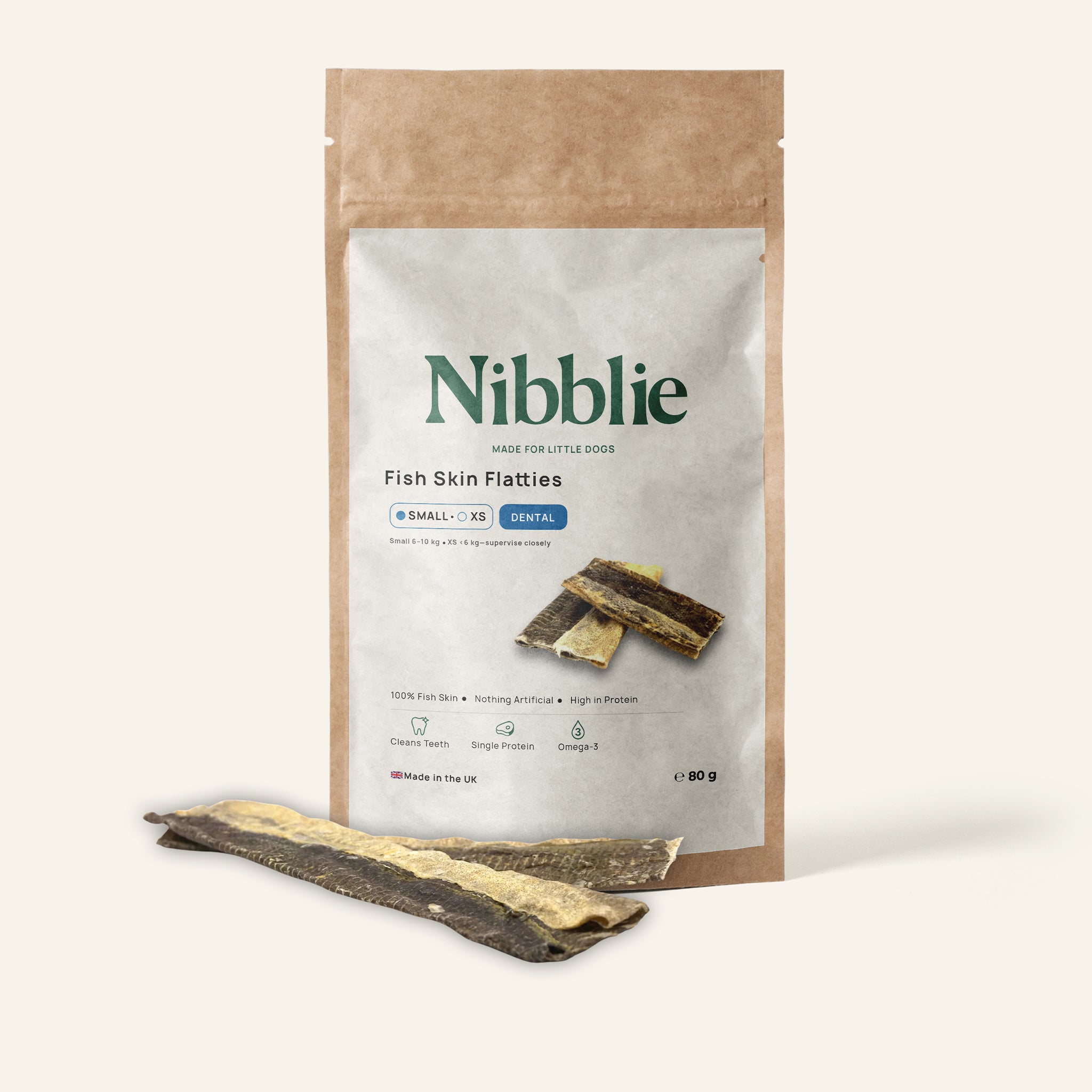 Nibblie Fish Skin Flatties 80g pack on warm linen with flatties in front; textured dental chews for small dogs.