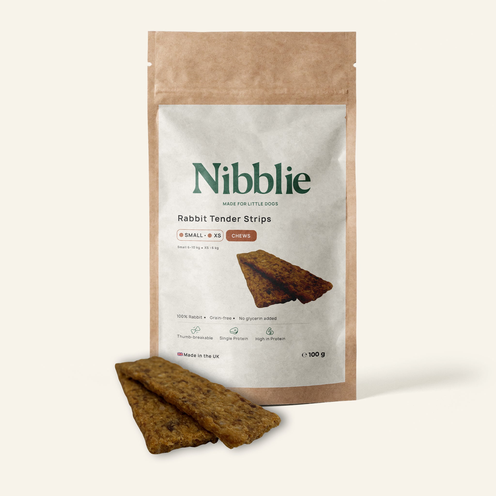 Nibblie Rabbit Tender Strips 100g pack on warm linen with strips in front; single-protein chew for small dogs.